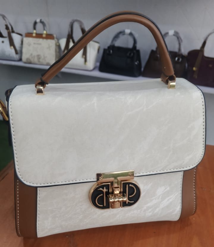 Cream flap bag with tan trim and gold turnlock
